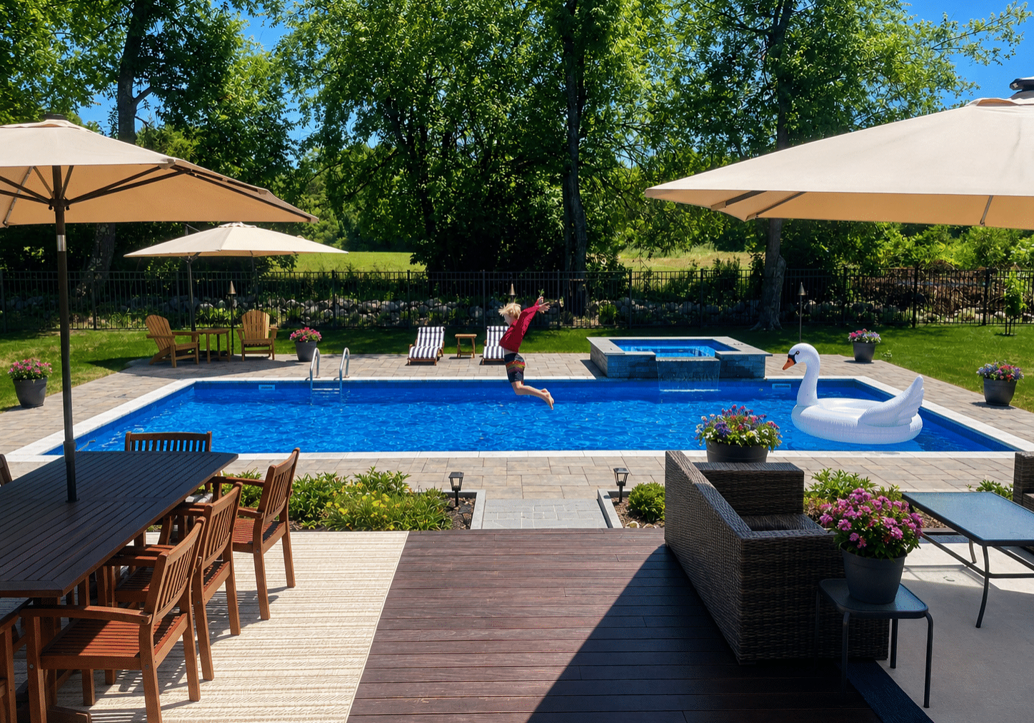 A person jumps into a backyard pool with a swan float, highlighting expert pool design services.