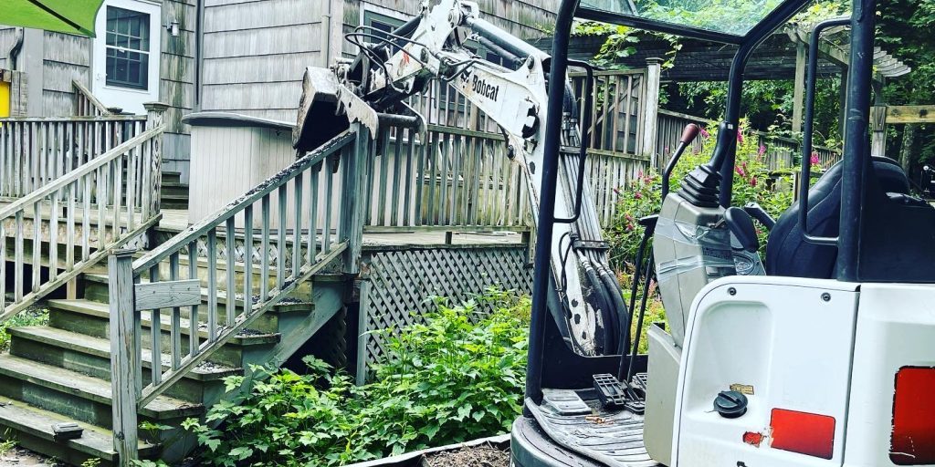 Demolishing an old deck with backhoe.