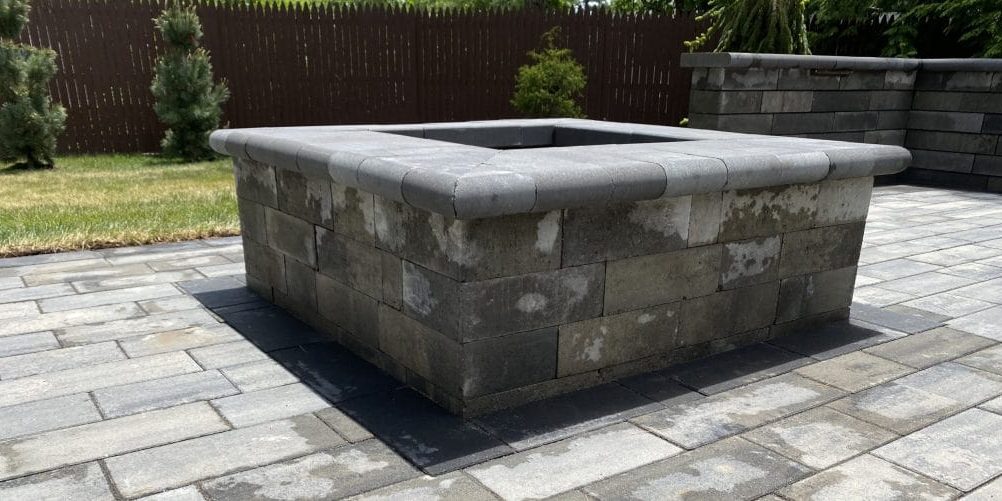 Precast concrete block fire pit on patio.