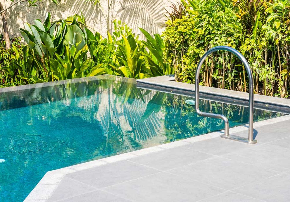 Sleek pool with landscaping and stone paver pool deck.